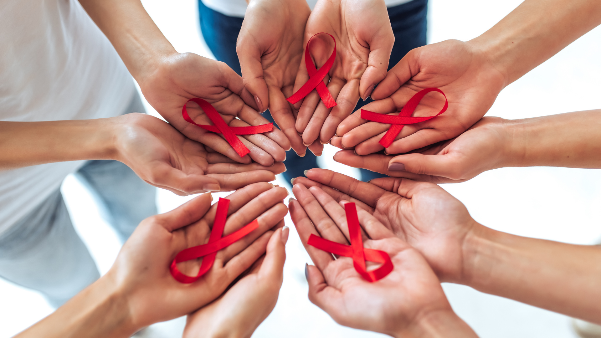 L'immagine rappresenta un insieme di mani aperte che mostrano un fiocco rosso, simbolo della lotto contro l'HIV