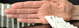 immagine di una mano che ferma dei mattoncini del domino
